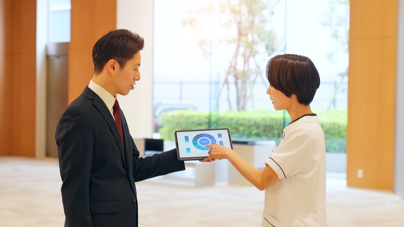 医院のスタッフにタブレットで説明する担当者